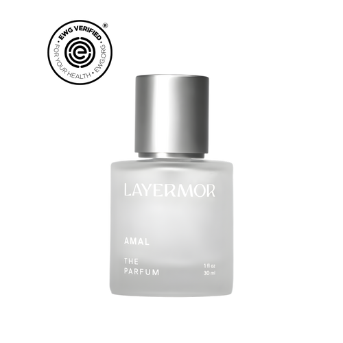 A frosted glass bottle of LAYERMOR AMAL THE PARFUM with a metallic silver cap, shown on a plain white background with a circular BPA-free verified badge in the top-left corner.